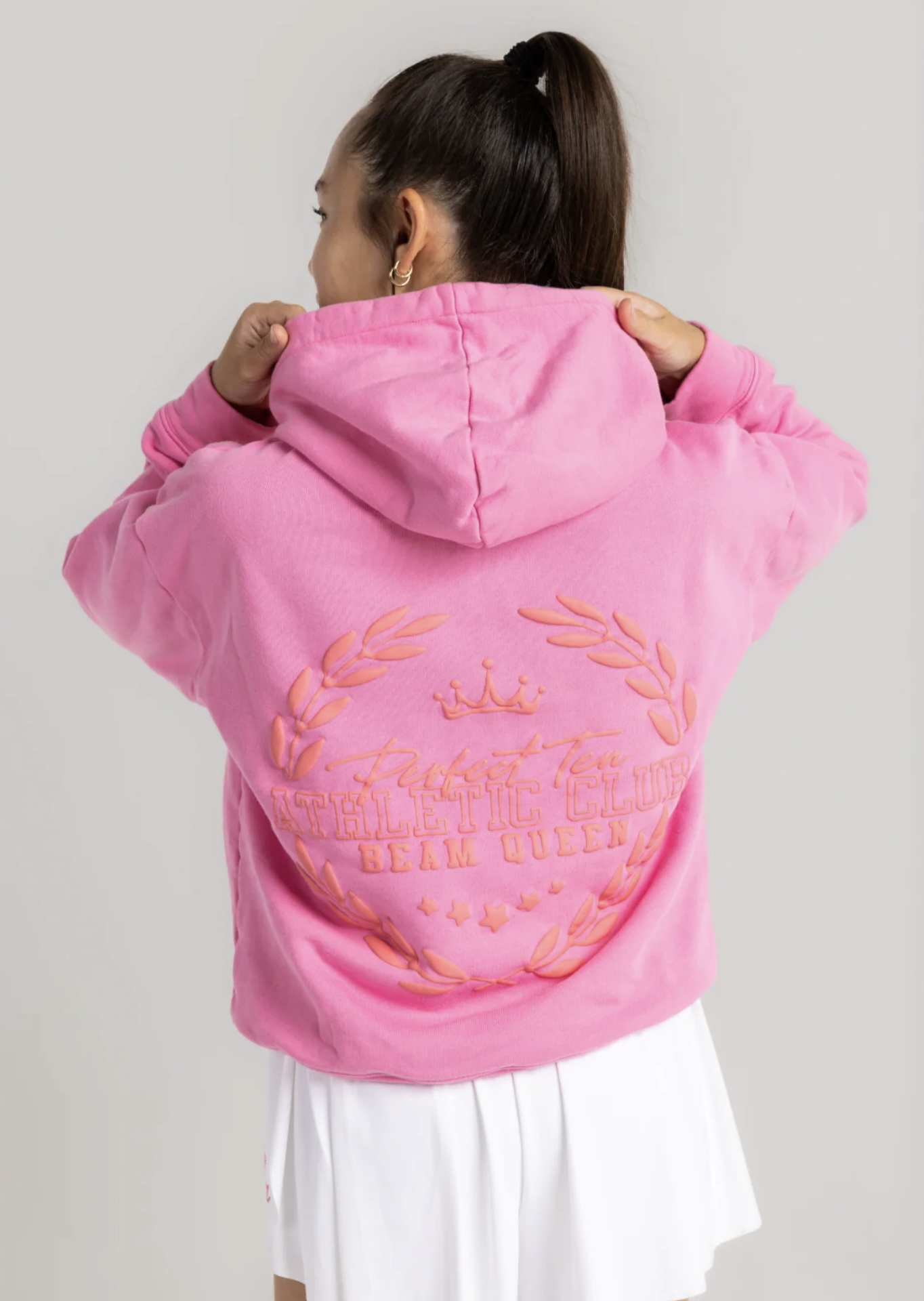 Model seen from behind in pink hoodie with crest
